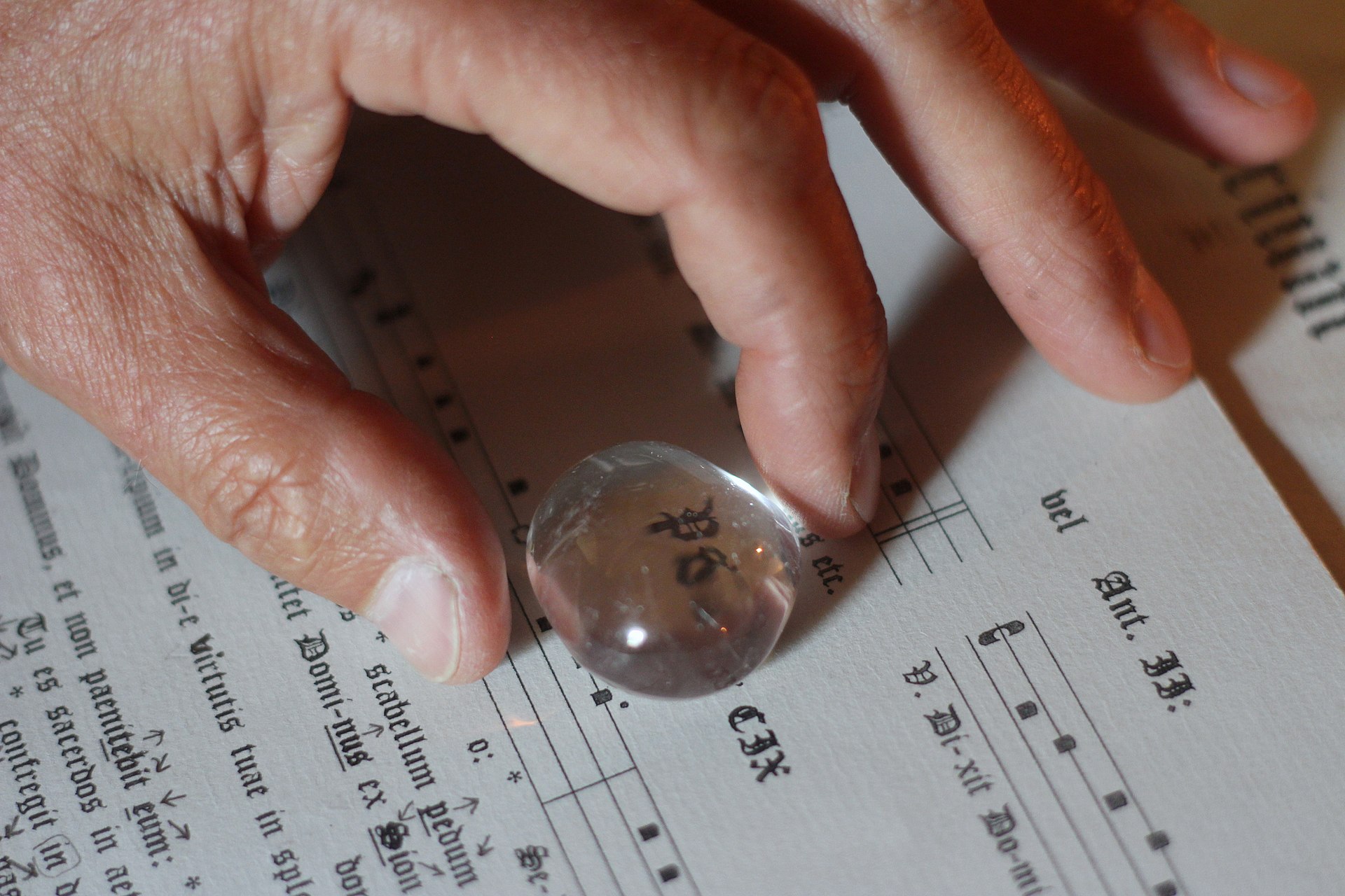 An image of a stone held over text on a paper, showing the increasing size of the text due to focused light