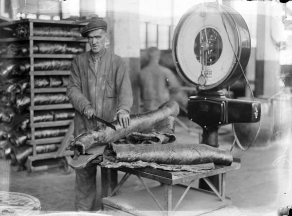 A Dunlop factory worker weighing and cutting rubber