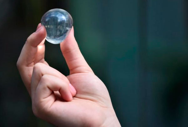 A hand containing an edible water ball